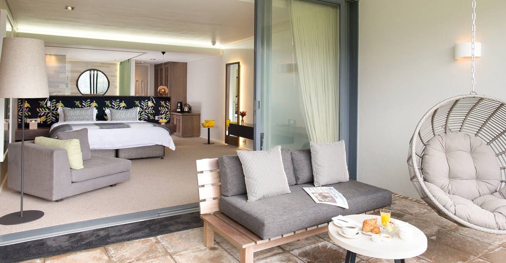 Luxurious king bed with plush white linens, elegant wooden furnishings, and large windows overlooking vineyard landscapes at a high-end South African wine estate hotel room