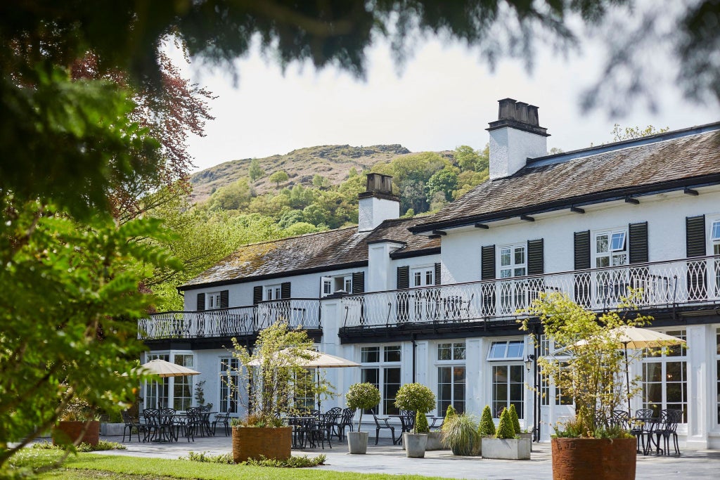 Elegant stone manor hotel nestled in lush Lake District landscape, featuring classic British architecture and manicured gardens under soft natural light