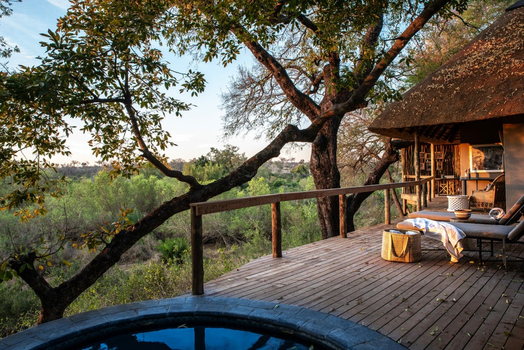 Luxurious African safari lodge with thatched roof deck overlooking a vast savanna, featuring private plunge pool and elegant furnishings