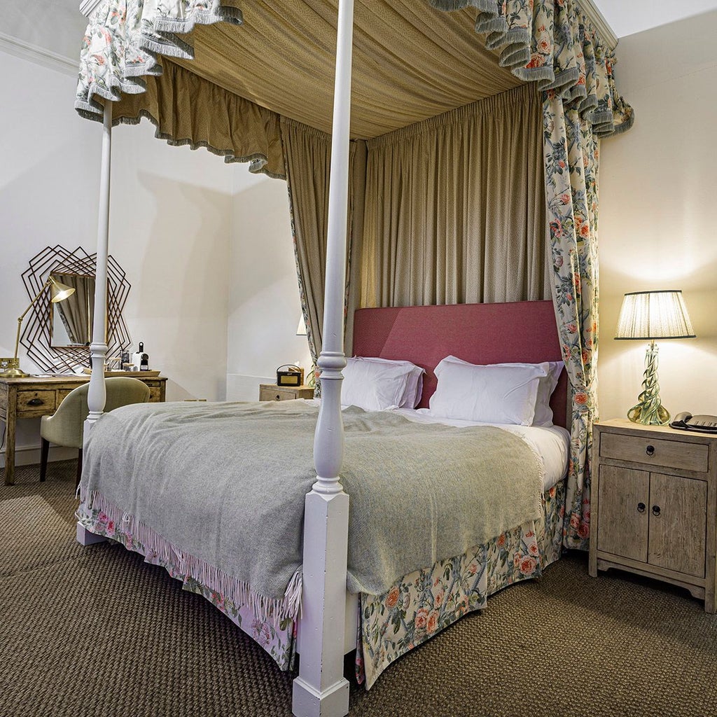 Elegant four-poster bed with rich wooden furnishings in a spacious Deluxe Suite at The Scenset Malton Hotel, showcasing British luxury and refined hospitality