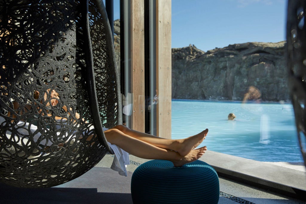 Luxurious glass-walled hotel nestled in rugged Icelandic landscape, with minimalist Nordic design and panoramic views of dramatic volcanic terrain at dusk