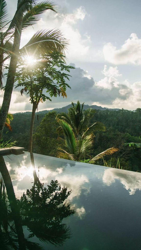 Open-air jungle villa with floor-to-ceiling windows, private infinity pool, and panoramic views of lush Balinese rainforest canopy