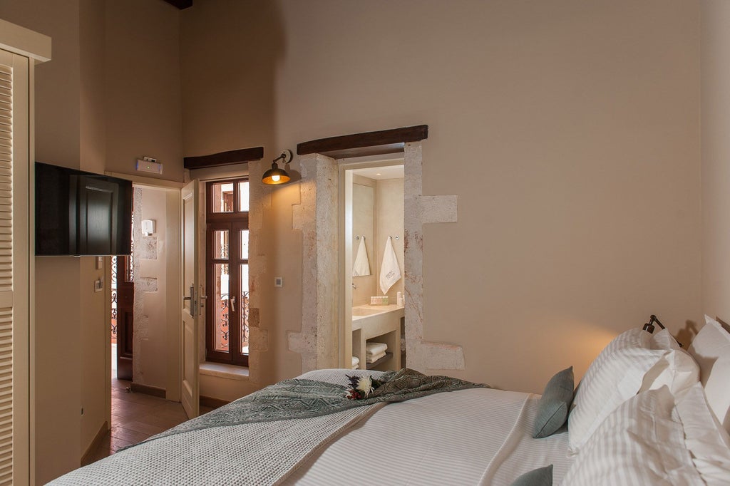 Elegant standard double room with white linens, minimalist design, wooden floors, and soft natural light in a Greek boutique hotel setting