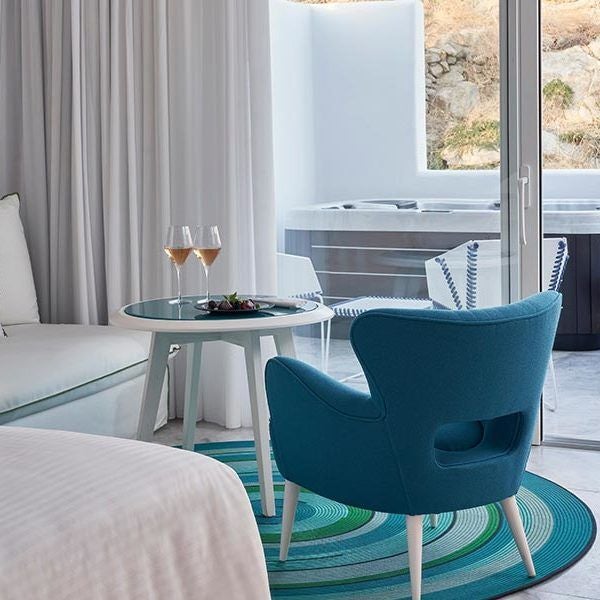 Luxurious white minimalist hotel room with panoramic Aegean Sea view, sleek modern design, crisp linens, and elegant Myconian architectural elements