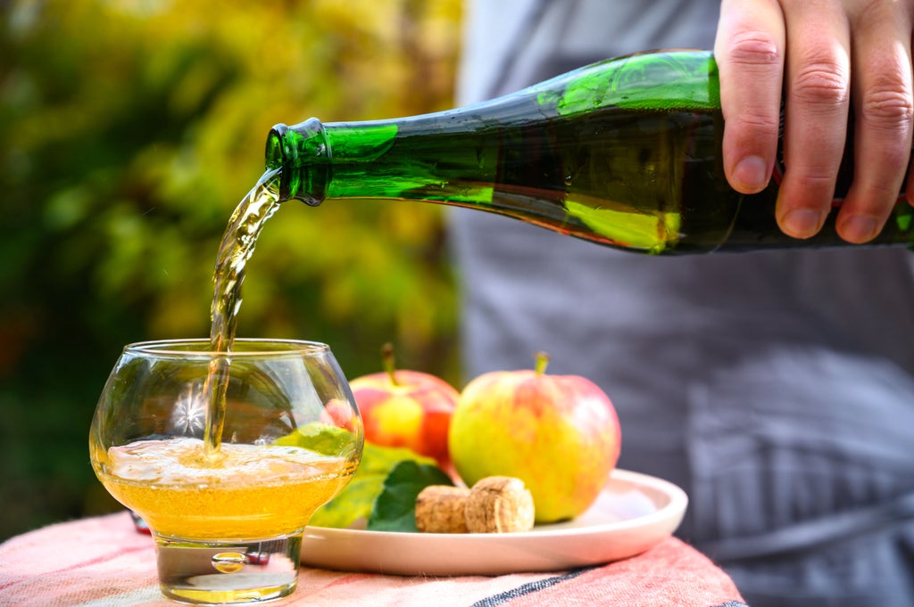 Historic Norman farmhouse with rustic wooden beams and stone walls, featuring displays of artisanal cider and Calvados bottles amid barrels