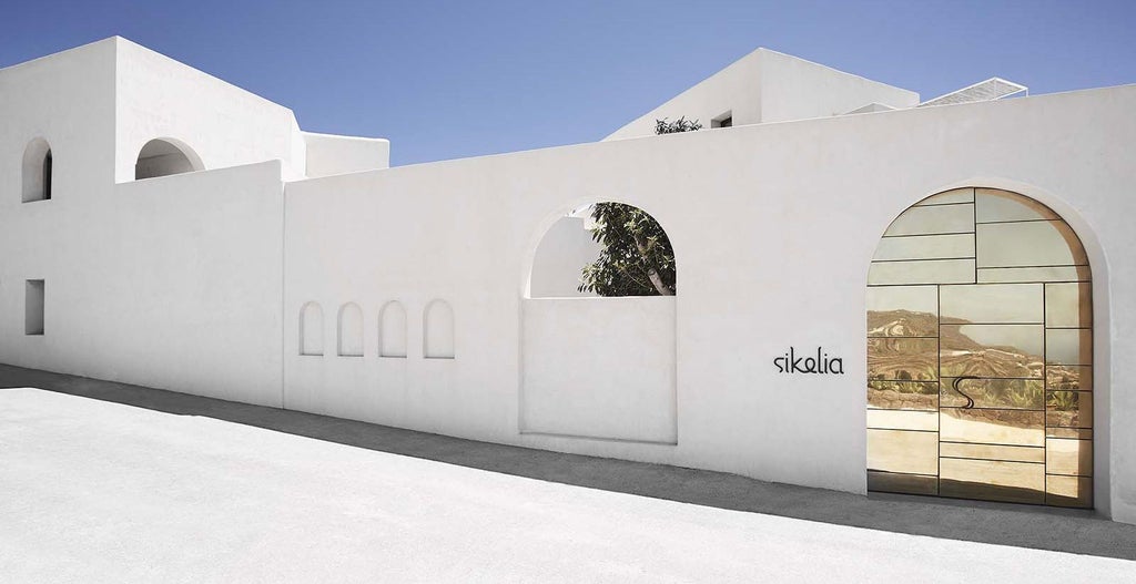 Luxurious whitewashed Sicilian hotel with minimalist design, stone walls, and elegant outdoor terrace overlooking scenic Mediterranean landscape