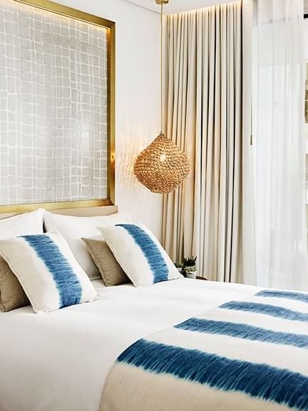 Luxurious white and blue deluxe hotel room at Nobu Hotel Ibiza Bay, featuring modern minimalist design with sea-inspired color palette and elegant furnishings