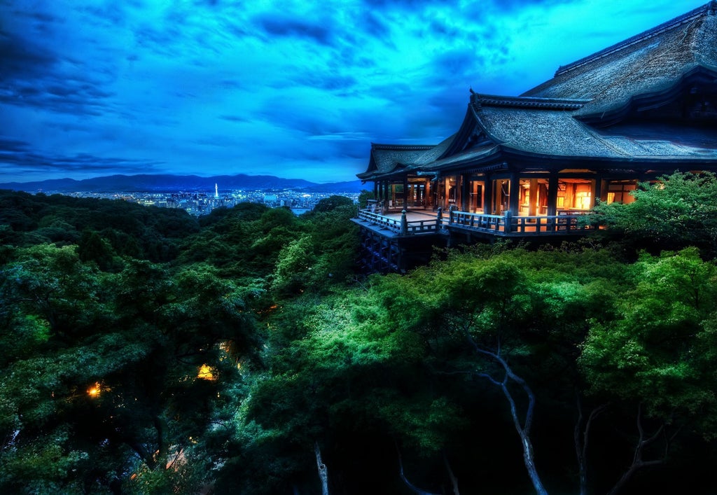 Modern luxury hotel with traditional Japanese stone garden, reflecting pool and wooden pavilions nestled against mountain backdrop in Kyoto