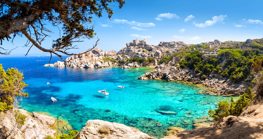 Elegant yacht cruising turquoise waters along Sardinia's Costa Smeralda, with emerald hills and luxurious villas dotting the coastline