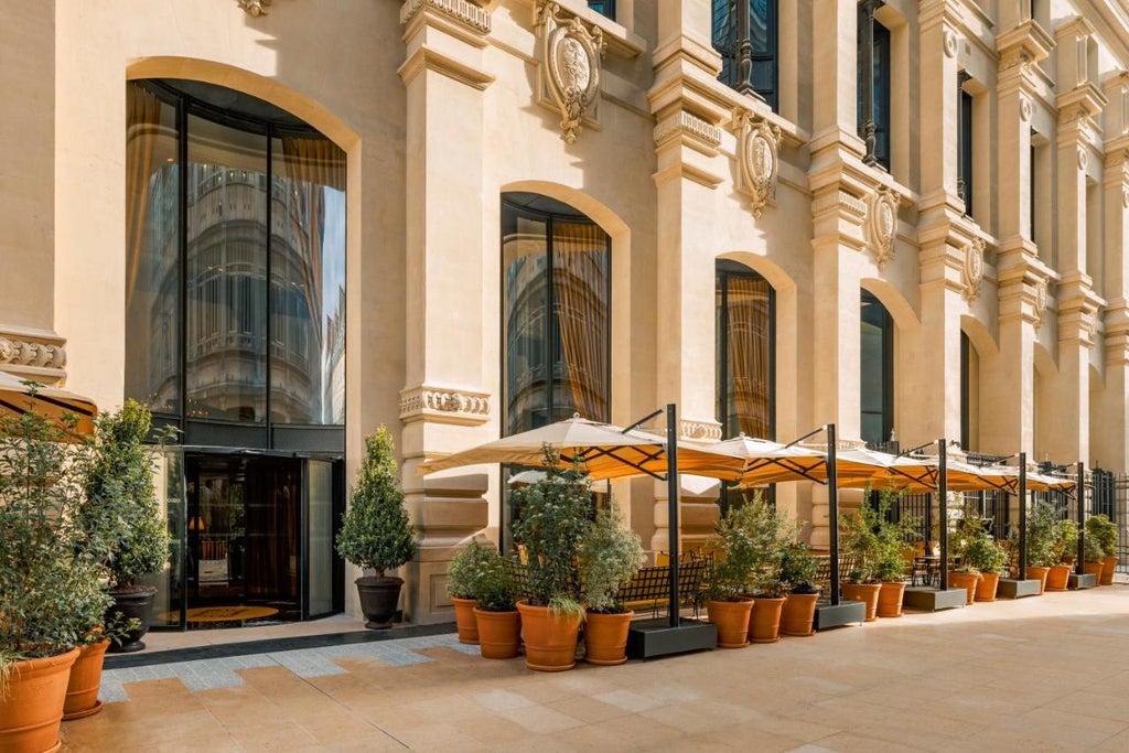 Elegant Parisian boutique hotel facade with ornate gold lettering, arched windows, and classic limestone architecture at dusk