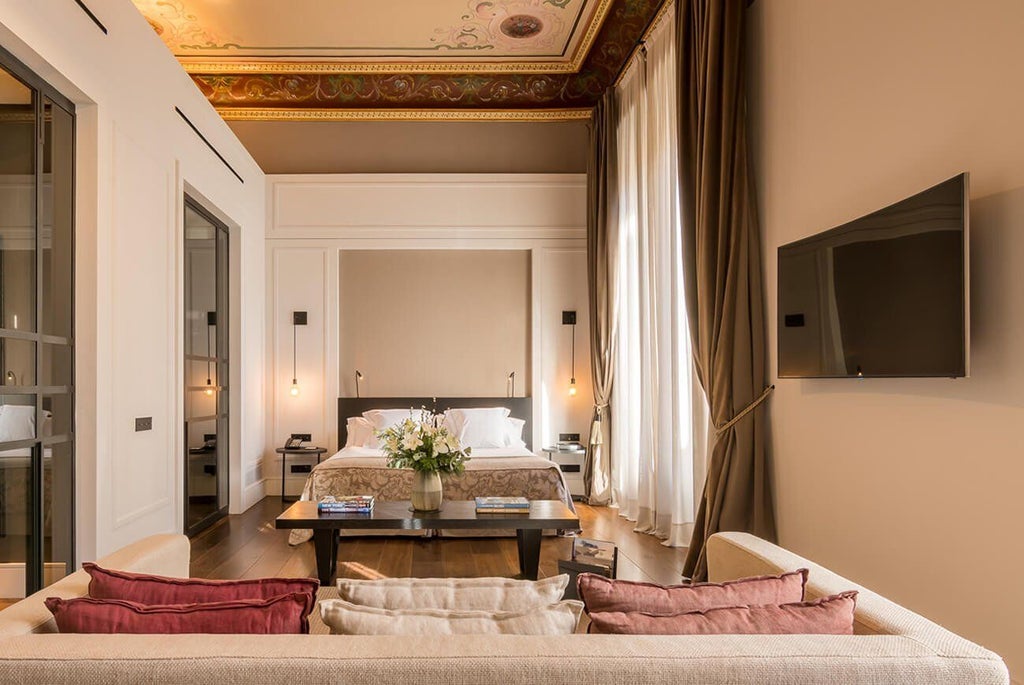 Elegant suite at Sant Francesc Hotel Singular in Spain, featuring plush furnishings, warm neutral tones, and sophisticated architectural details with vintage charm