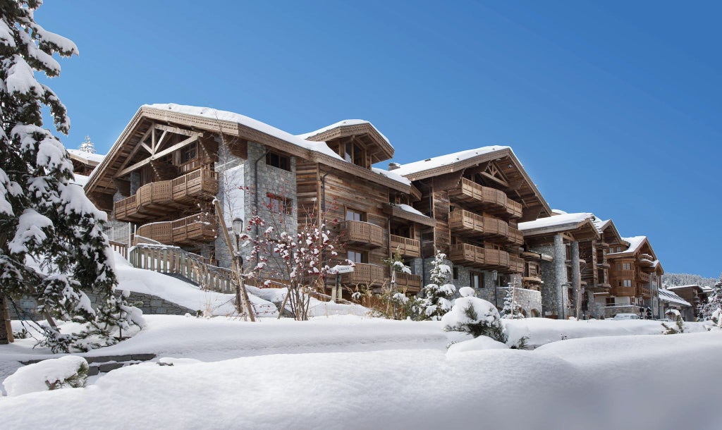 Luxurious alpine ski resort with modern chalet architecture, snow-covered landscape, and elegant Six Senses design blending seamlessly with French mountain scenery