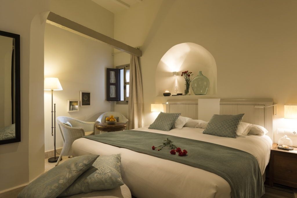 Elegant Spanish hotel room with ornate wooden furniture, arched window, and intricate tile flooring in warm neutrals at Hotel Balcón de Córdoba