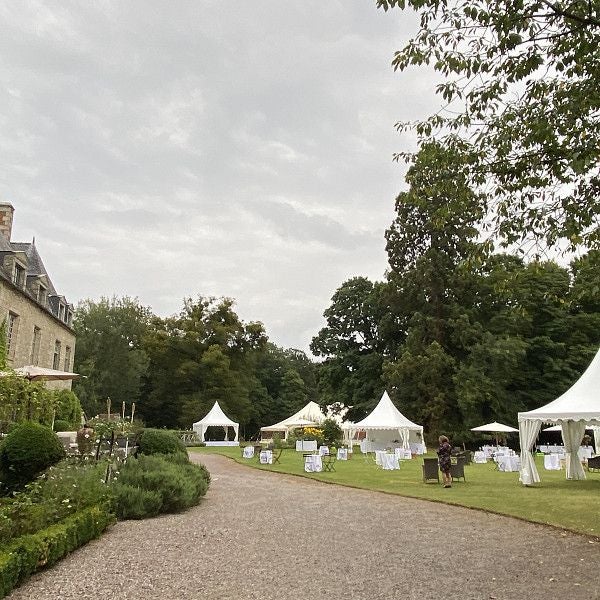 Elegant 18th-century French château hotel with stone facade, manicured gardens, and soft golden sunlight illuminating historic architectural details.