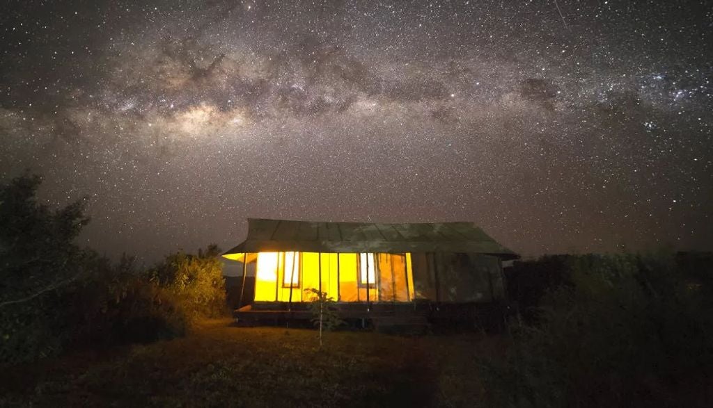 Luxury safari tent perched on Ngorongoro Crater rim with canvas walls, wooden deck and panoramic savanna views at golden hour