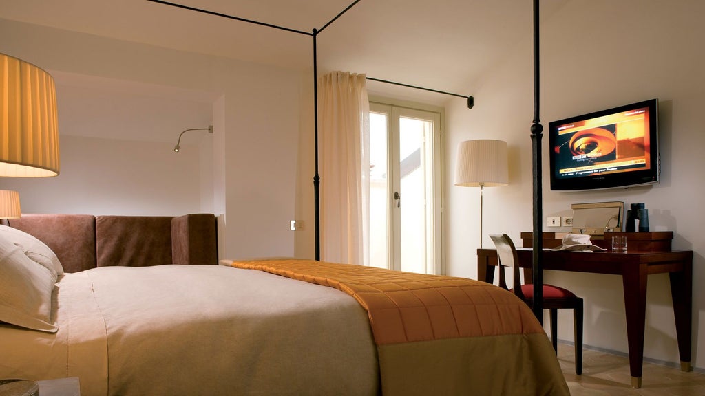 Elegant Italian suite with rustic stone walls, luxurious king bed, antique wooden furnishings, and soft ambient lighting in Umbrian countryside hotel