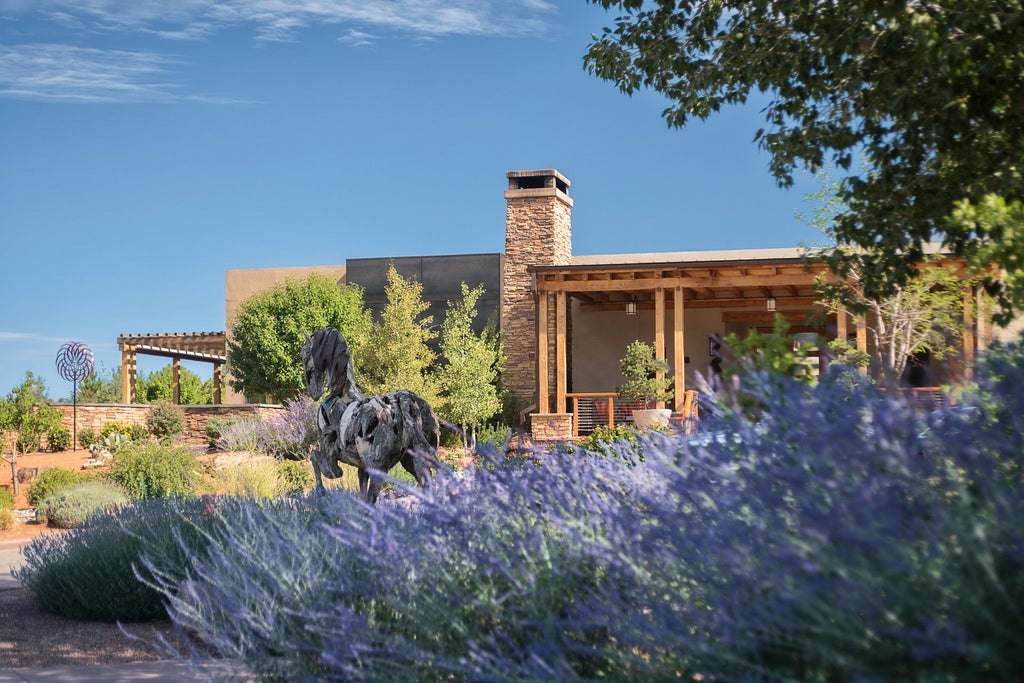 Luxurious adobe-style resort nestled in New Mexico hills, featuring terracotta walls, private balconies and mountain views at sunset