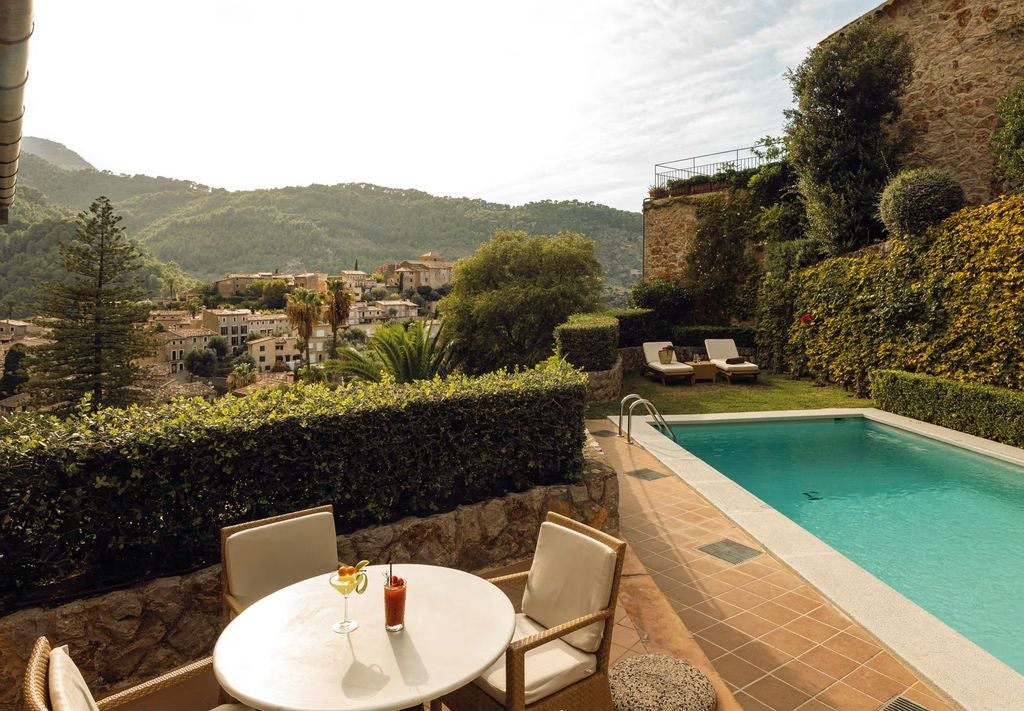 Elegant Mediterranean suite with terrace views, featuring draped canopy bed, antique furnishings and warm natural lighting throughout