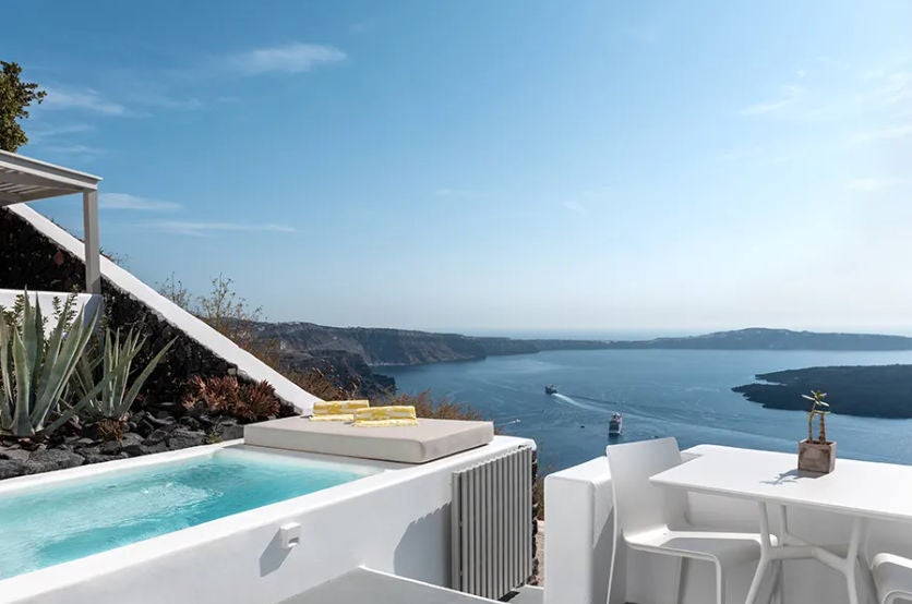 Elegant Junior Suite with private plunge pool overlooking Santorini caldera, featuring white minimalist decor and curved architecture