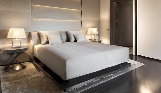 Modern luxury hotel room with grey tones, marble bathroom, designer furniture and cityscape views through floor-to-ceiling wi