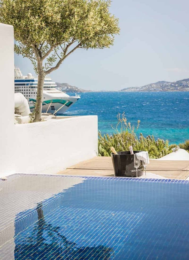 Luxurious Grace Suite in Mykonos with private plunge pool overlooking azure Aegean Sea, featuring minimalist white decor and elegant outdoor terrace