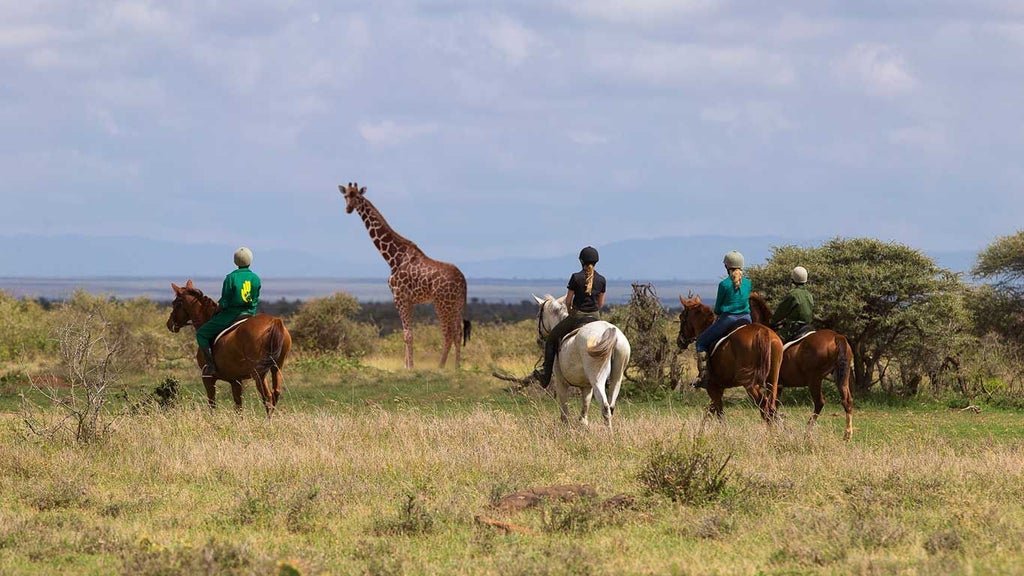 Luxurious safari tented camp overlooking dramatic Kenyan wilderness, with contemporary canvas suites and sweeping savanna landscape at sunset