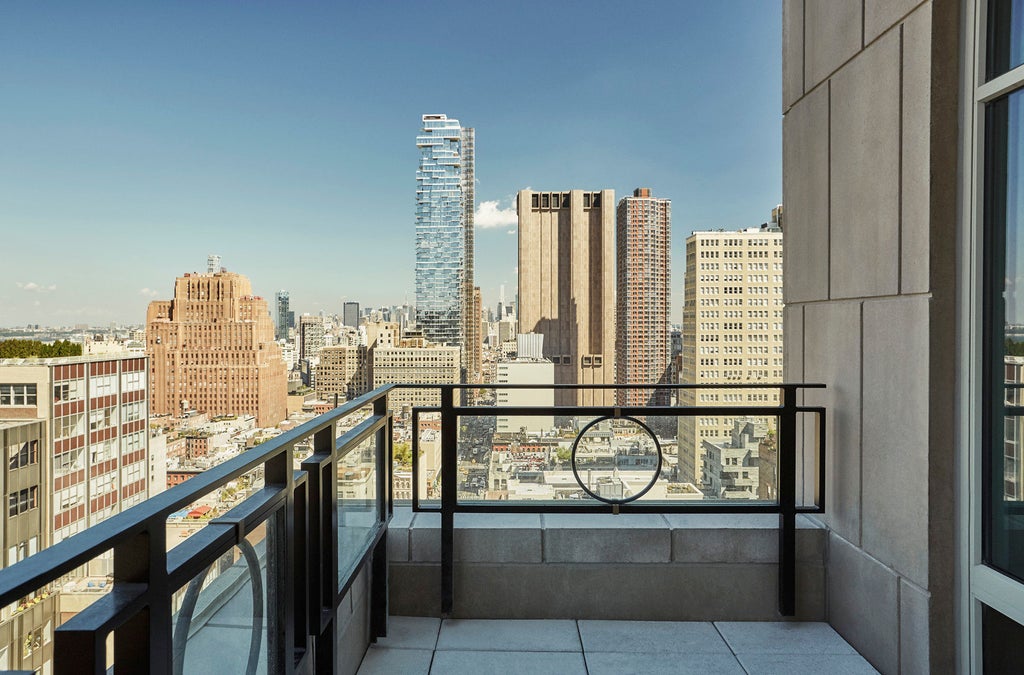 Art Deco-style luxury hotel facade with gleaming glass tower, white stone base, and illuminated Four Seasons signage in downtown Manhattan