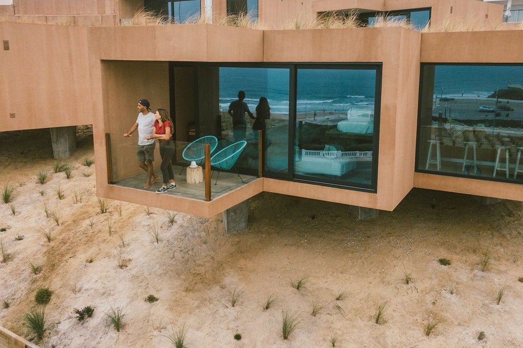 Minimalist beachfront bungalow with wooden deck, ocean view, and sleek design at Noah Surf House in scenic coastal Portugal landscape