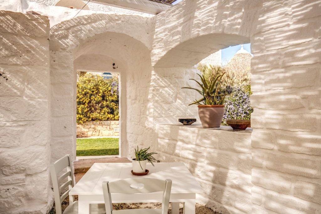 Rustic stone Masseria with white-washed walls, lush olive groves, and golden Puglian sunlight, showcasing authentic Italian countryside luxury