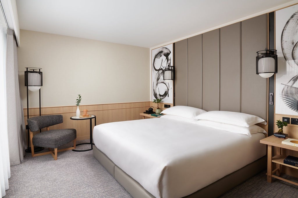 Elegant Nobu hotel deluxe room with contemporary design, plush white bedding, minimalist decor, and warm neutral tones overlooking urban landscape