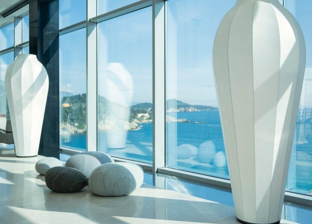 Sleek modern hotel perched on cliffside above Adriatic Sea, featuring glass facade, private beach and panoramic balconies in Dubrovnik