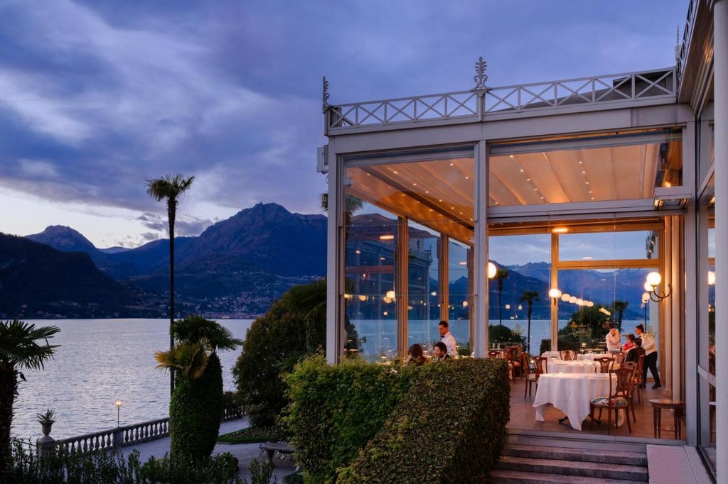 Opulent Renaissance-style hotel with grand columns and ornate balconies overlooking Lake Como, framed by manicured gardens and Alps