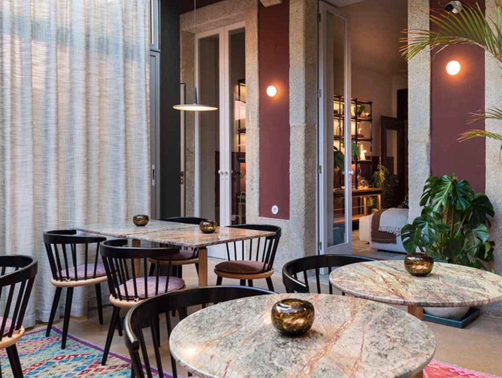 Elegant boutique hotel exterior with arched windows, ornate wrought-iron balconies, and traditional Portuguese blue-tiled facade in Porto