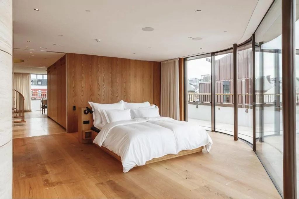 Minimalist Scandinavian hotel room with panoramic fjord view, sleek wooden furnishings, neutral color palette, and expansive floor-to-ceiling windows