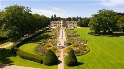 Luxurious three-story Georgian manor hotel with pristine white facade, manicured gardens, and elegant architecture nestled in the scenic Yorkshire countryside.