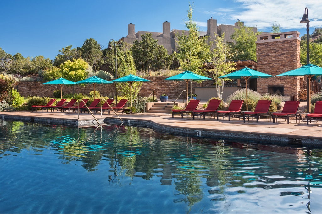 Adobe-style resort with terracotta walls and wooden beams nestled in desert landscape, illuminated by warm sunset light against mountains