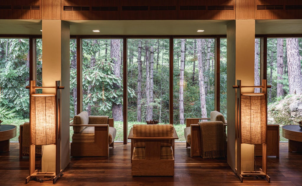 Modern luxury lodge with stone and wood facade nestled in pine forest, featuring traditional Bhutanese architectural details and mountain views