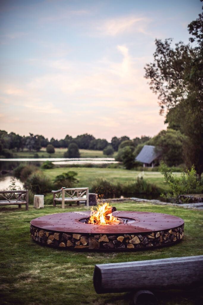 Luxurious French château hotel with stone walls, surrounded by lush green countryside, featuring elegant architecture and tranquil natural landscape at dusk