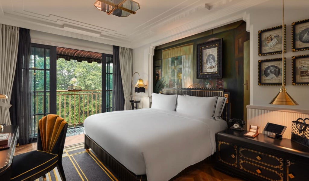 Elegant colonial-style Premier Suite with ornate gold accents, velvet furniture, floor-to-ceiling windows and luxury Vietnamese decor details