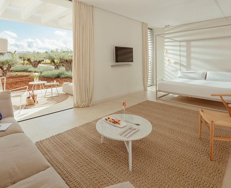 Luxurious white-walled suite with modern minimalist design, king-sized bed, wooden floors, and sleek contemporary furnishings in Spanish boutique hotel