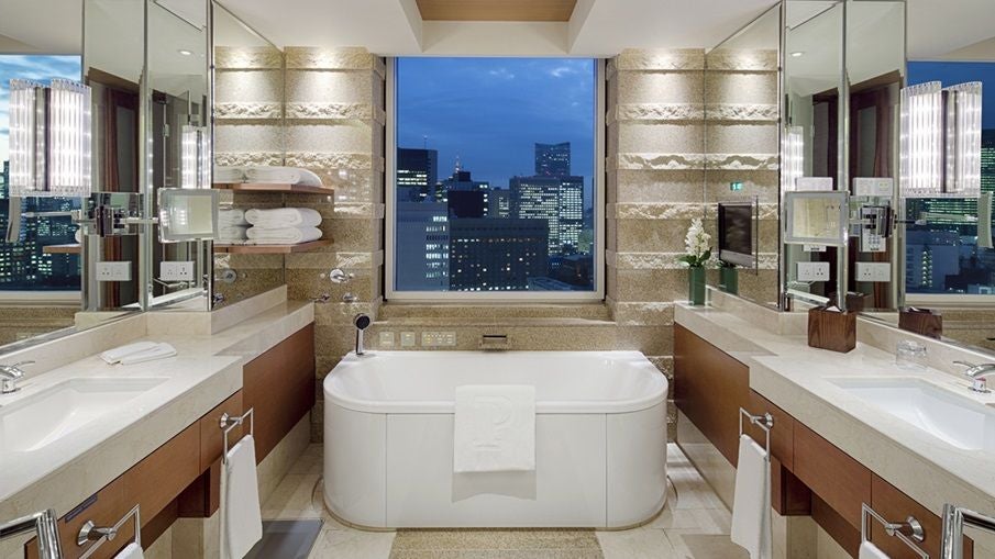 Elegant Hibiya Suite at Peninsula Tokyo with city skyline view, modern minimalist decor, floor-to-ceiling windows, and luxurious king-sized bed with crisp white linens