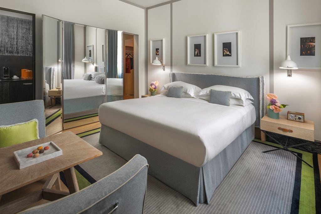 Luxurious hotel room in Rome with elegant neutral tones, plush bedding, and sleek modern furnishings overlooking a historic Italian cityscape