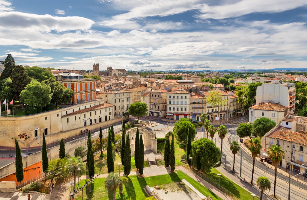 Historic city square in Montpellier featuring elegant limestone buildings, ornate architecture and a sun-drenched Mediterranean atmosphere