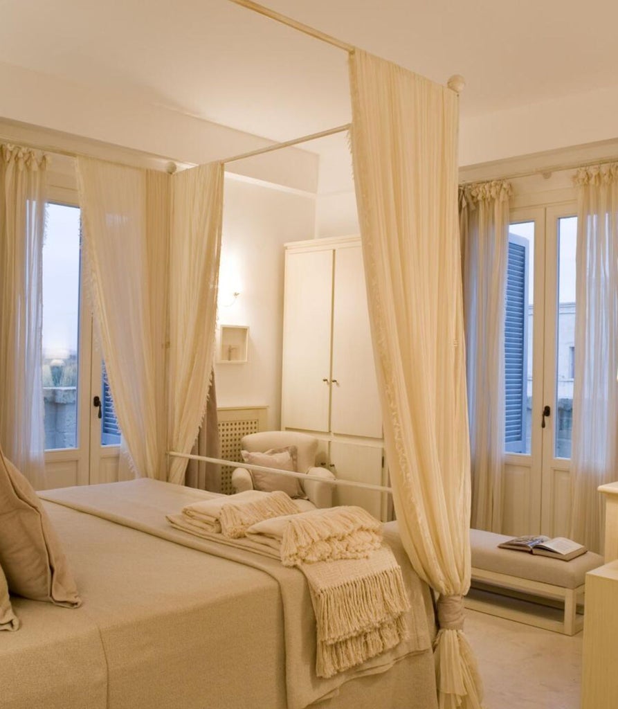 Elegant Italian hotel suite with vaulted stone ceiling, ornate chandelier, white linen bed, and natural light through arched windows