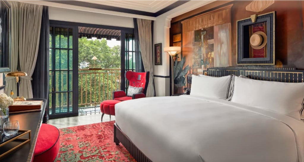 Elegant hotel room with French colonial decor, featuring king bed, vintage furnishings, marble bathroom and city views of Hanoi