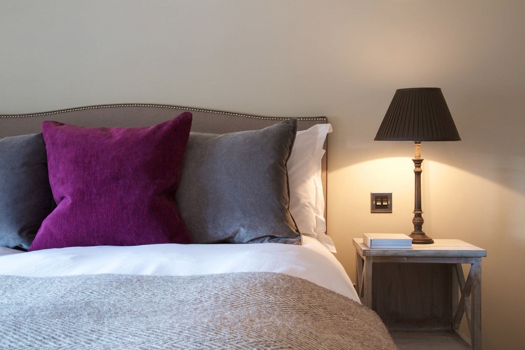 Spacious, modern hotel apartment with plush king-sized bed, elegant wooden furnishings, and large windows offering natural light at scenset Kings Head Hotel in the United Kingdom.