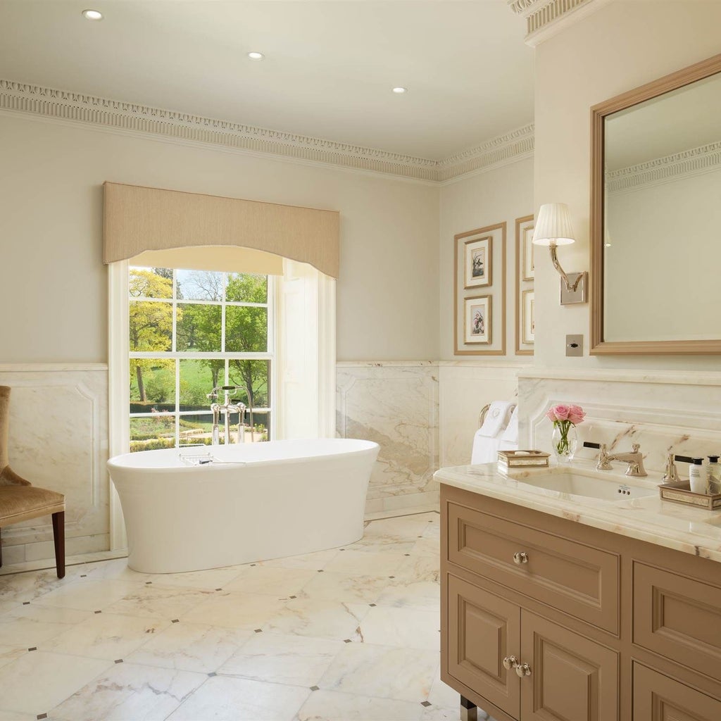 Elegant grand suite with plush king bed, sophisticated neutral color palette, luxurious marble bathroom, and expansive windows overlooking manicured grounds at Grantley Hall