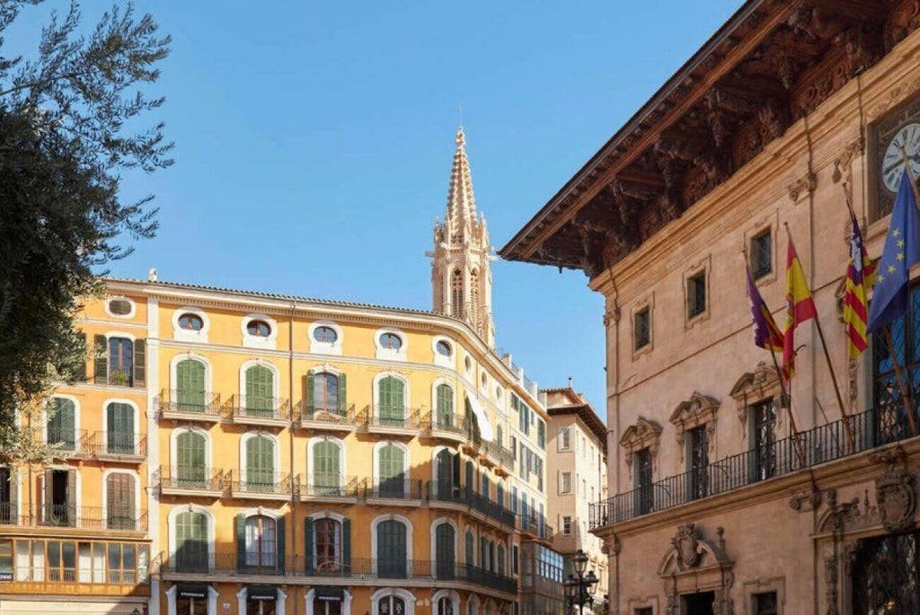 Elegant boutique hotel facade in Palma de Mallorca, with restored historic stone building, luxurious architectural details, and warm Mediterranean sunlight