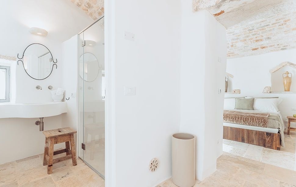 Rustic stone deluxe lamia room at Borgo Canonica with elegant white linens, arched ceiling, and warm terracotta tones in a traditional Pugliese setting