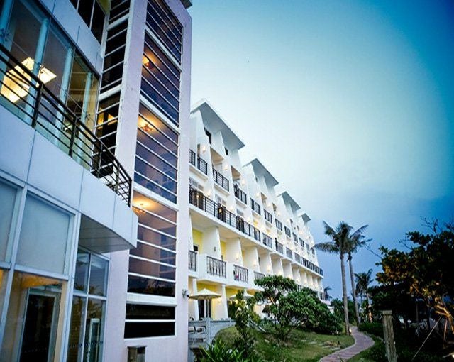 Elegant white modern resort building with curved architecture overlooking tropical gardens and infinity pools near Kenting beach